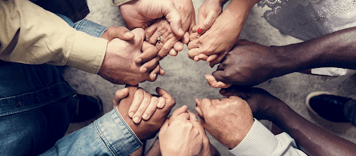 A circle of clasped hands from a diverse group of people