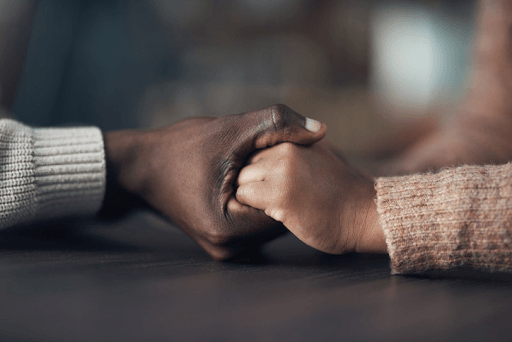 Close-up of two people holding hands on a wooden table